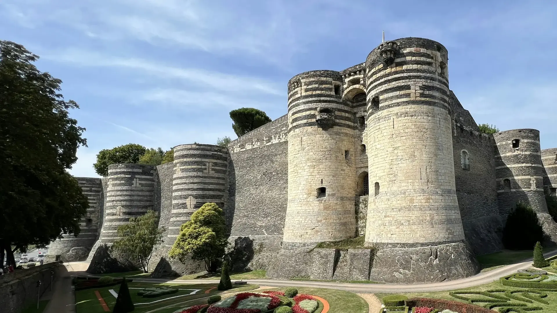 Pruhované válcové věže Château d'Angers se tyčící nad parterem příkopové zahrady